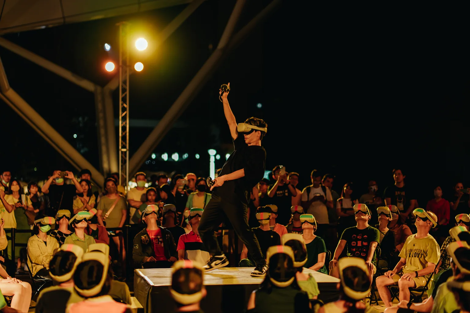 A live performer stands at the centre of Free UR Head, surrounded by seated participants wearing VR headsets