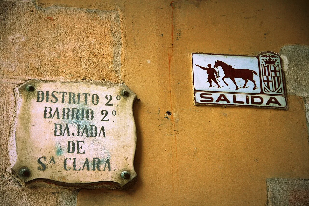 巴塞隆納牆上的Bajada de Santa Clara街牌,旁邊有帶馬匹圖像的Salida出口標示。