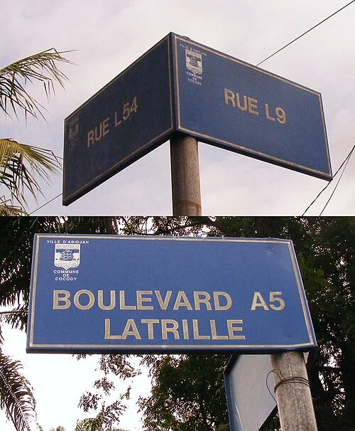 阿必尚的實拍街牌或門牌。交叉牌可讀RUE L9與RUE L8A，下面另有BOULEVARD A5 LATRILLE；字母數字組合本身就是道路識別的一部分。