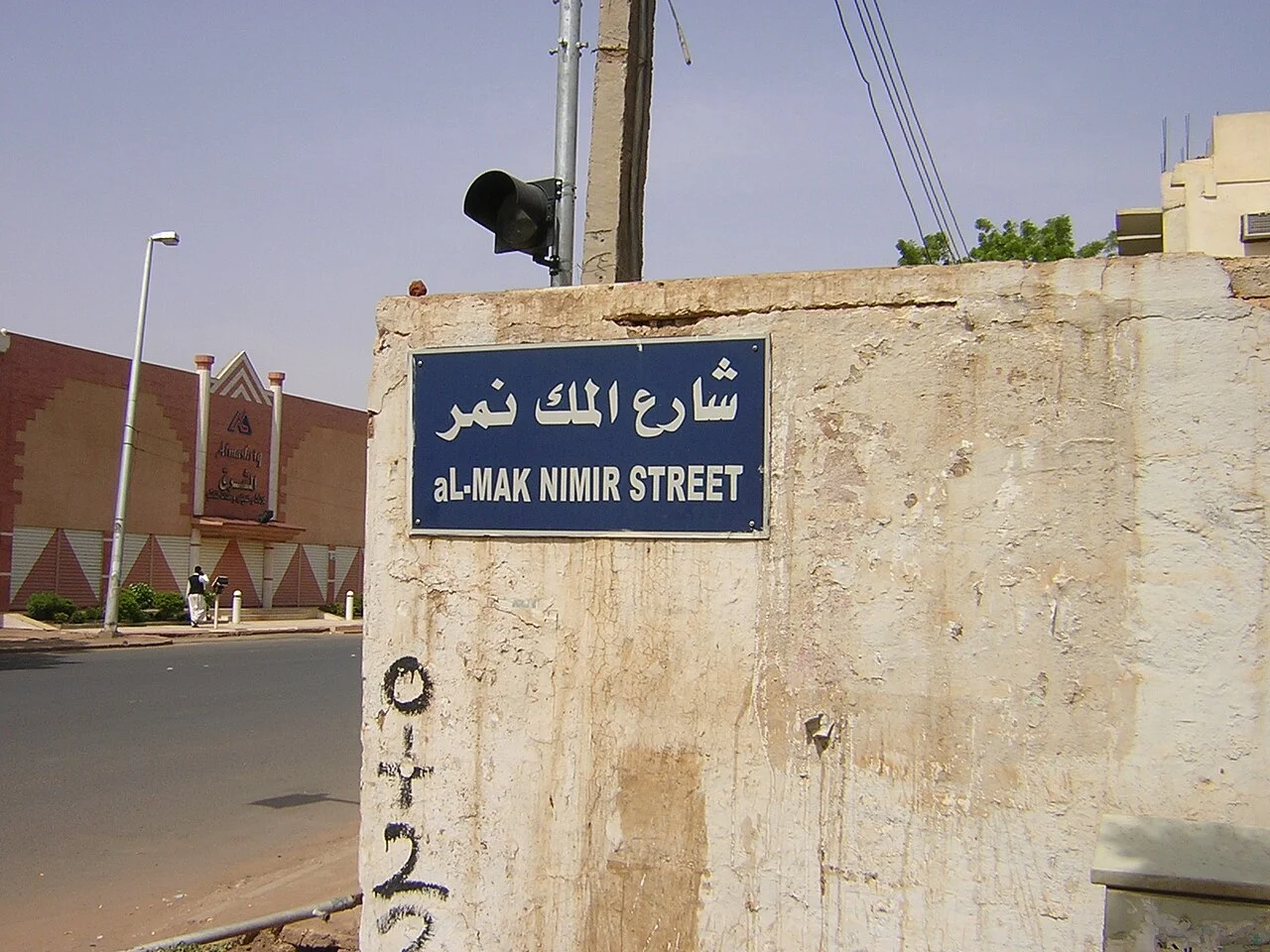 喀土穆的實拍街牌或門牌。牆上藍牌以上行阿拉伯文、下行al-MAK NIMIR STREET標示同一條街。