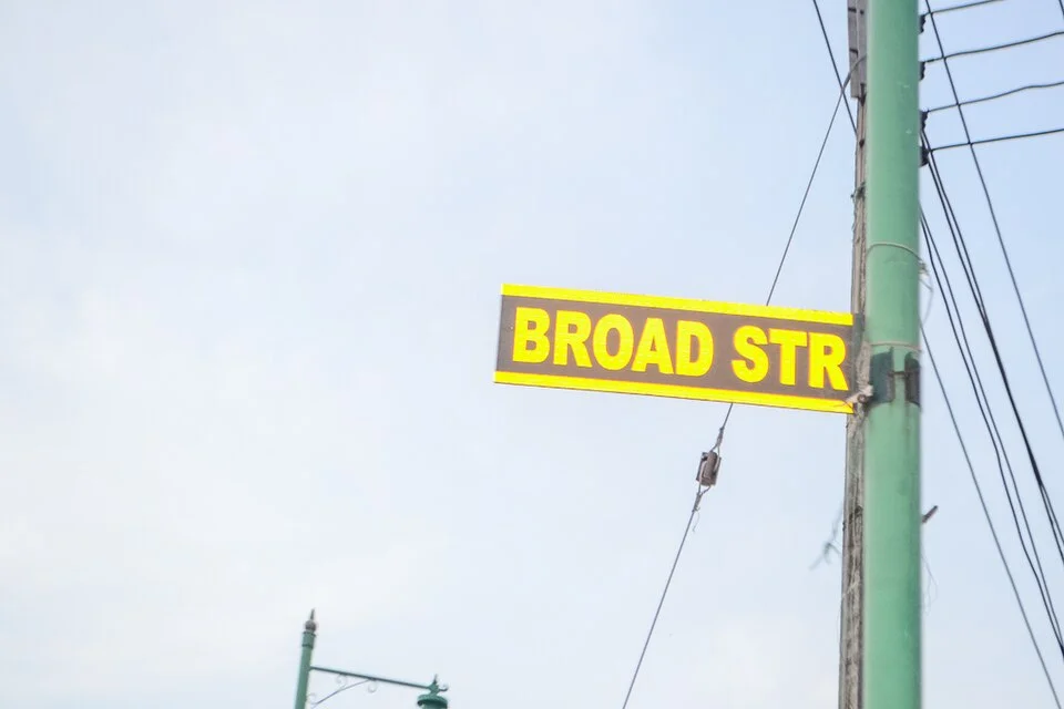 拉哥斯的實拍街牌或門牌。黃色窄牌上可讀BROAD STR，STR為牌面採用的Street縮寫形式。