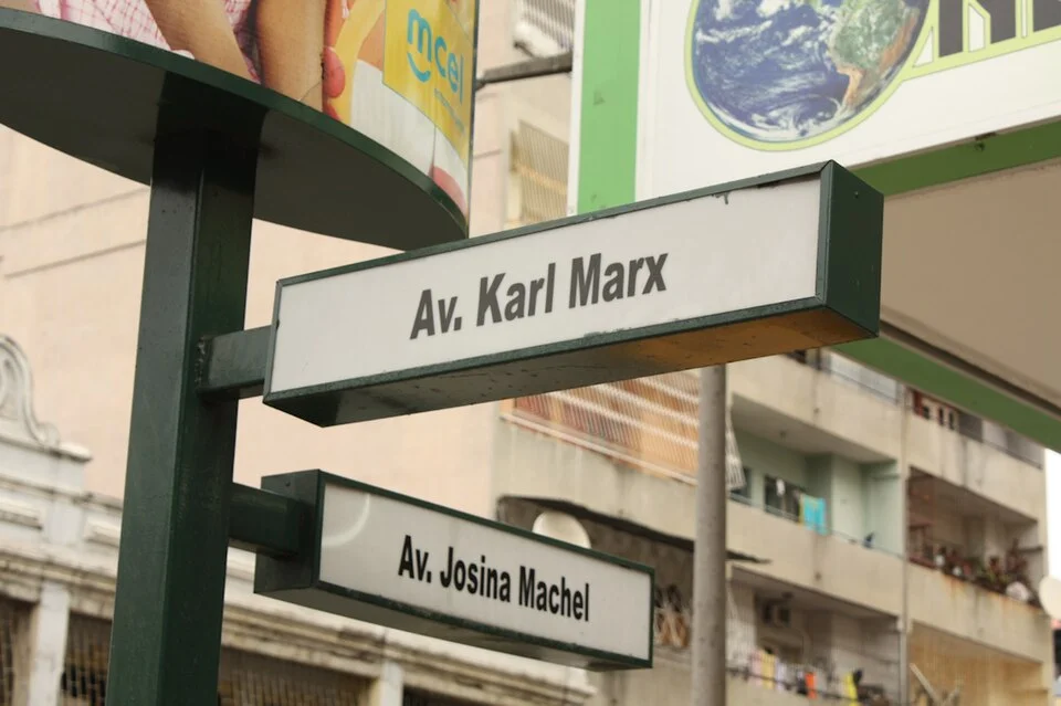 馬布多的實拍街牌或門牌。相互垂直的白底街牌可讀Av. Karl Marx與Av. Josina Machel；Av.是葡語Avenida的縮寫。