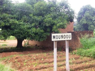 蒙杜入口實拍白底黑框牌，寫MOUNDOU，周圍為磚牆及樹木。