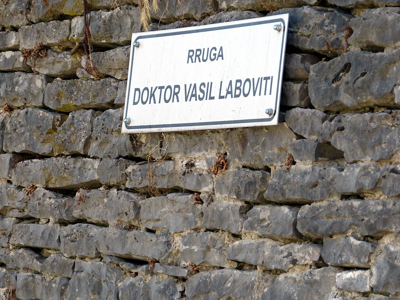 吉羅卡斯特的實拍街名或地址牌。牌面「RRUGA DOKTOR VASIL LABOVITI」為瓦西爾拉博維蒂醫師街；Rruga是阿爾巴尼亞語的街道用字。