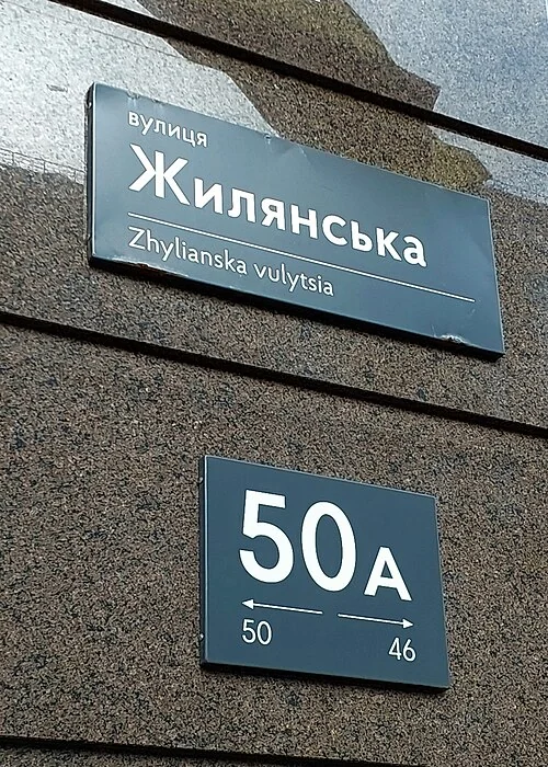 基輔的實拍街名或地址牌。街名牌「вулиця Жилянська／Zhylianska vulytsia」為日良斯卡街；下方「50A」為門牌，較小50與46及箭頭提示號碼方向。