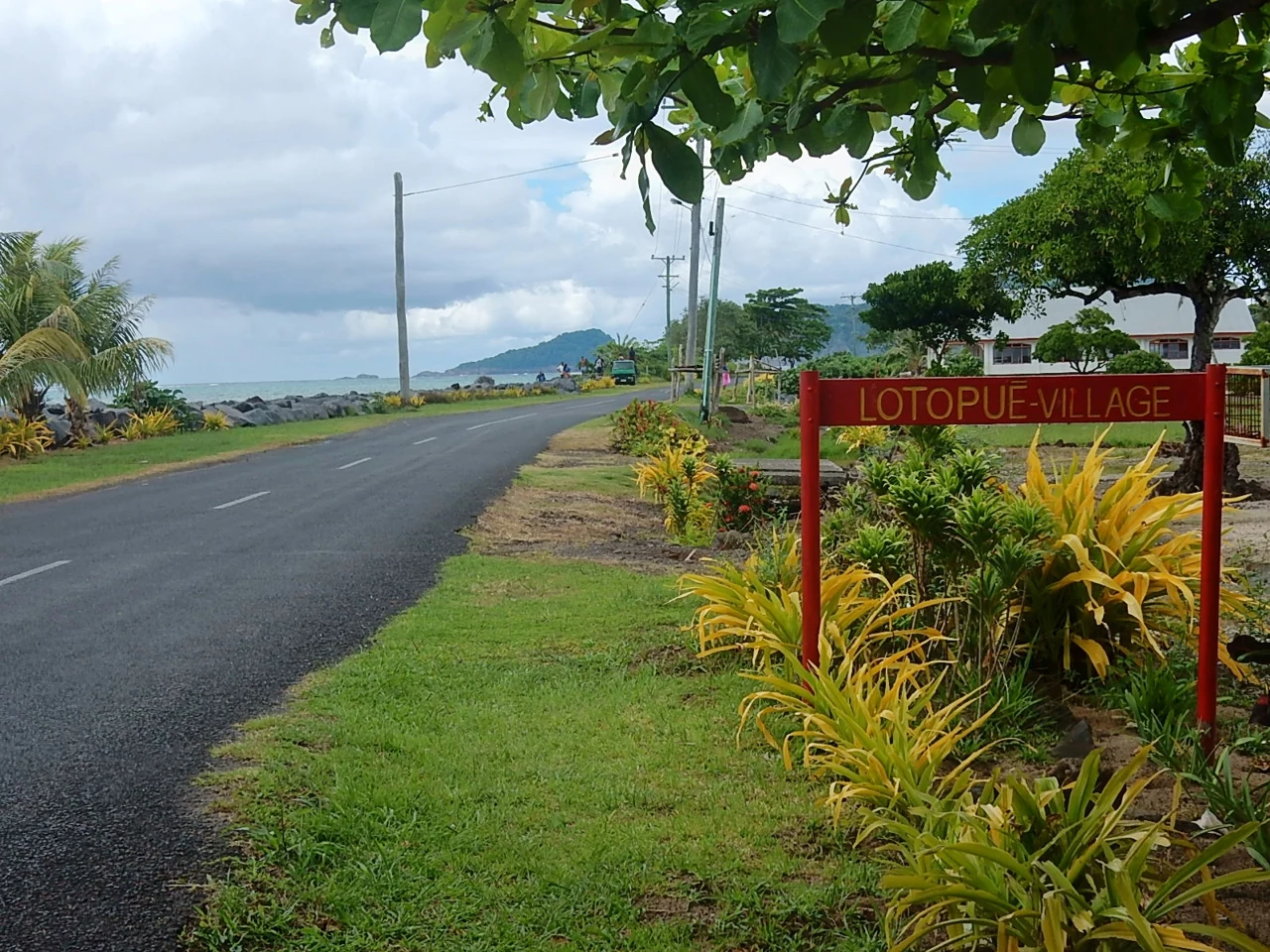 洛托普埃的實拍街名或地址牌。紅底黃字牌面實讀 LOTOPUE-VILLAGE，VILLAGE 表明聚落名稱；此處收錄為村落層級地址識別，不把它解作道路名稱或住宅門號。