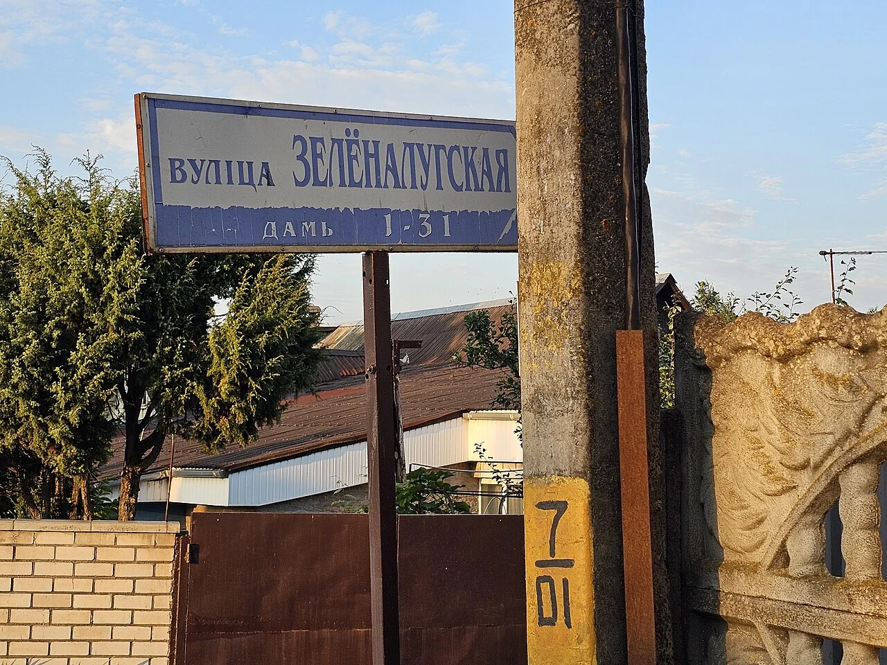 明斯克的實拍街名或地址牌。上行「ВУЛІЦА ЗЕЛЁНАЛУГСКАЯ」標示街名，下行「ДАМЫ 1–31」是住宅號碼範圍；立柱上的手寫7不當作已核實門牌。