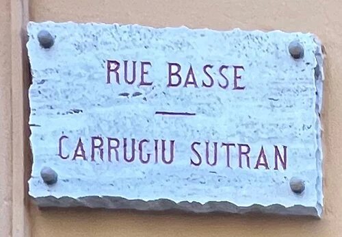 摩納哥城的實拍街名或地址牌。上行「RUE BASSE」與下行「CARRUGIU SUTRAN」是法文與摩納哥地方語的對應街名。