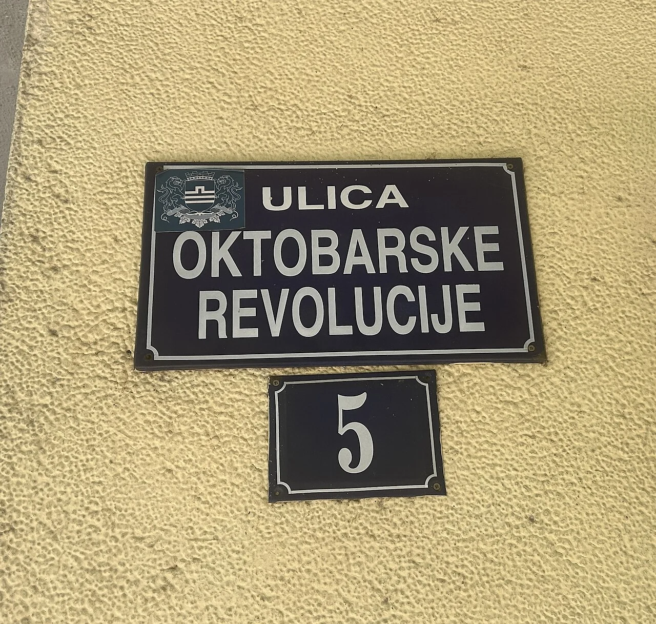 波德戈里察的實拍街名或地址牌。「ULICA OKTOBARSKE REVOLUCIJE」為十月革命街，下方獨立「5」牌為門牌。