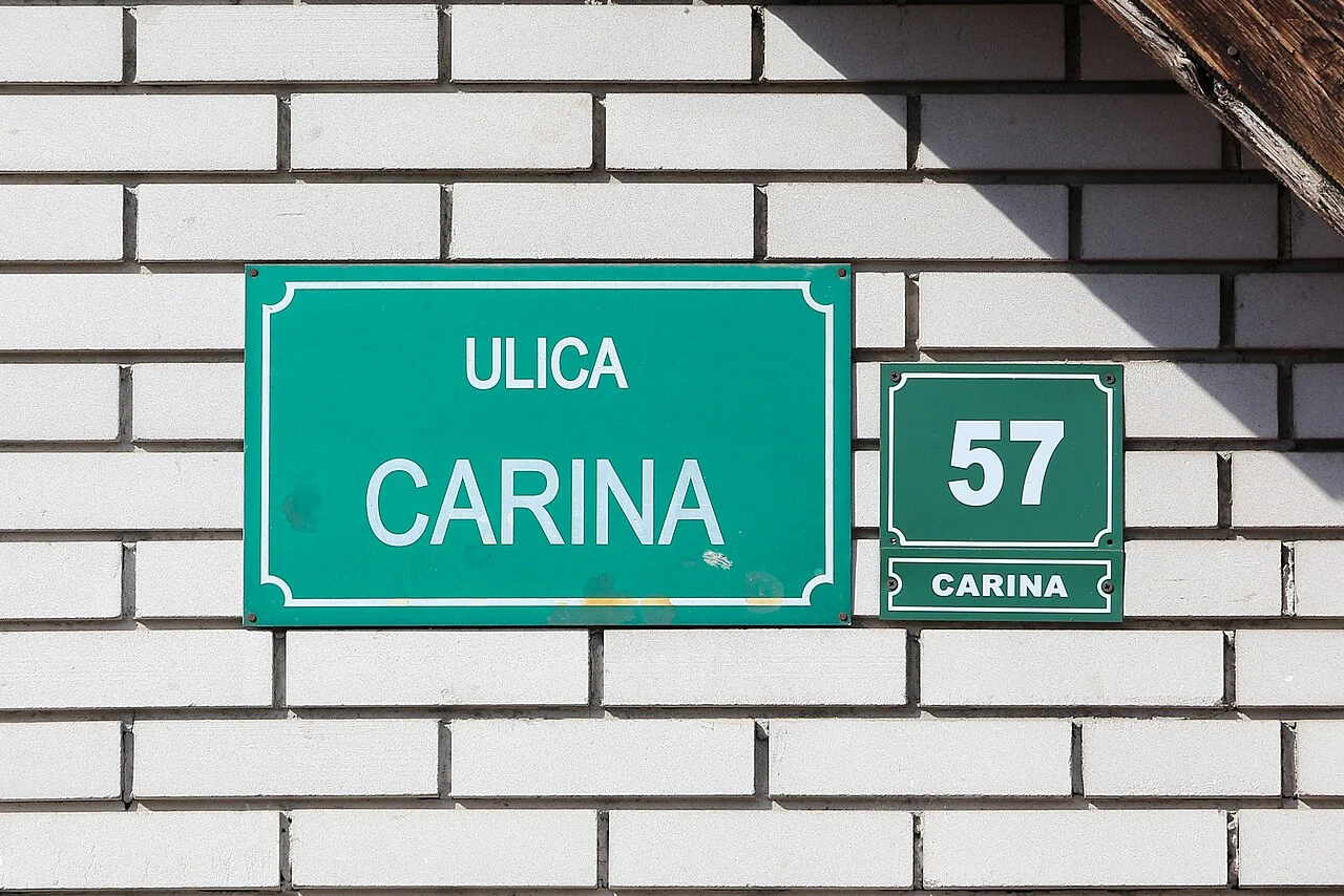 塞拉耶佛的實拍街名或地址牌。主牌「ULICA CARINA」為Carina街；右側獨立牌「57」是門牌，下方重複街名作地址確認。