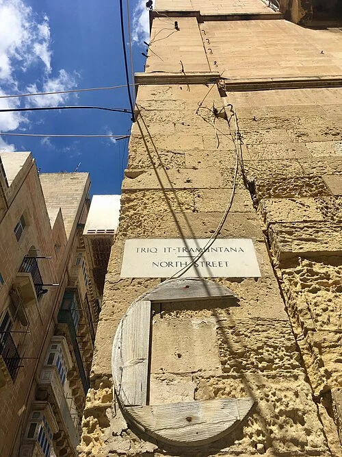 瓦萊塔的實拍街名或地址牌。上行「TRIQ IT-TRAMUNTANA」、下行「NORTH STREET」為同一道路的馬爾他語與英語名稱。