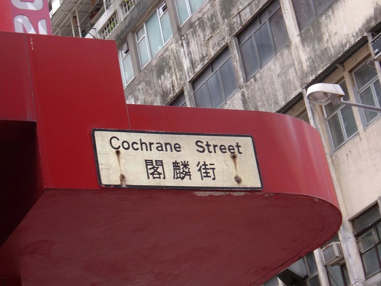 香港閣麟街的白底黑框街牌,英文 Cochrane Street 在上、中文閣麟街在下,牌面有鏽痕。