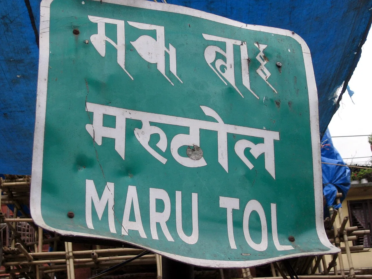 加德滿都馬魯街區的綠色街名牌，蘭札文、天城文及 MARU TOL 拉丁字母分成三行。