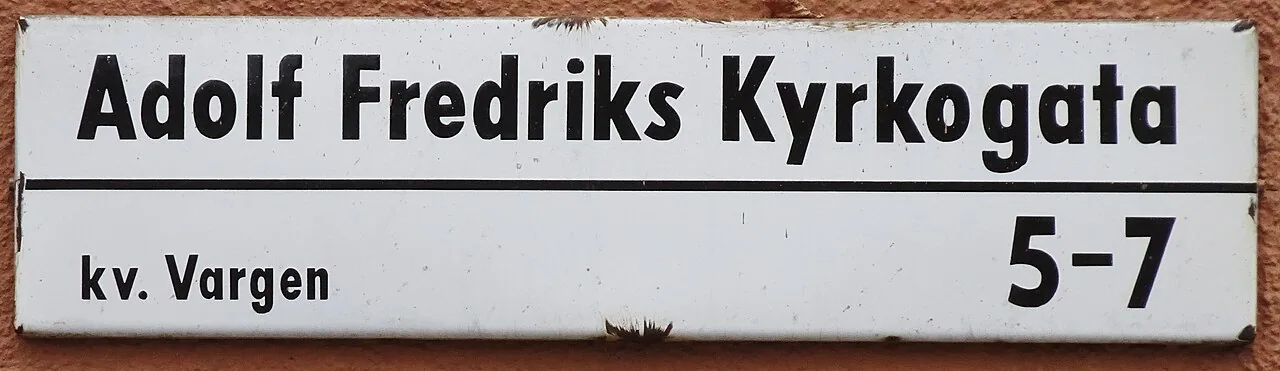 斯德哥爾摩Adolf Fredriks Kyrkogata白底黑字街牌,下方有kv. Vargen與5–7。