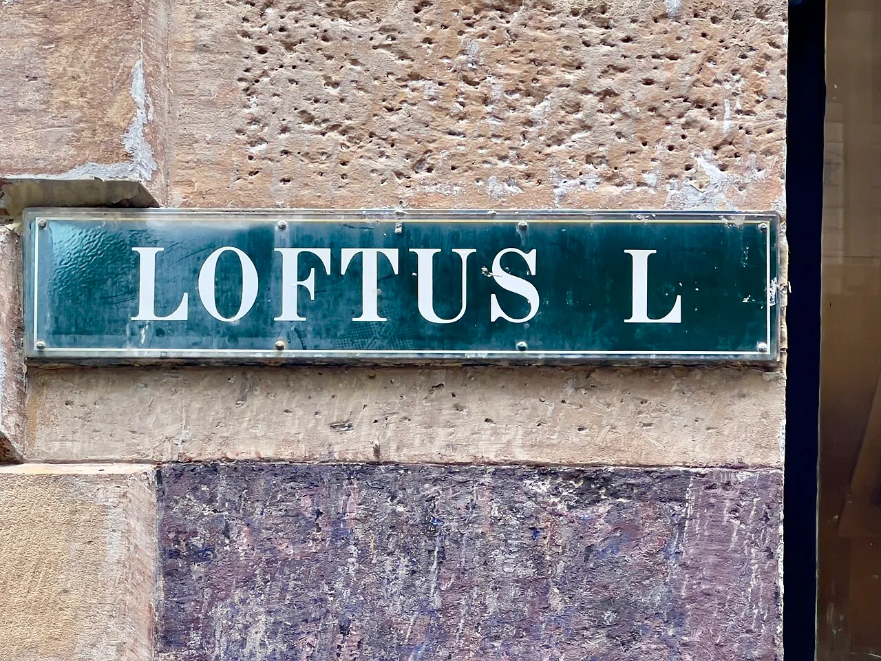 雪梨牆面上藍綠底白色襯線字Loftus L街牌，牌面帶反光，四周有框邊。