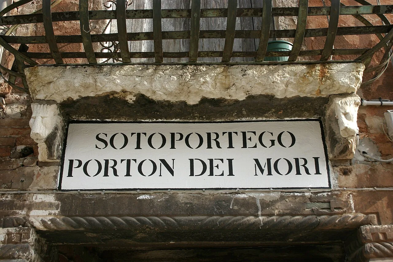 威尼斯磚石門楣上的黑框白底牆面字樣，寫Sotoportego Porton dei Mori。