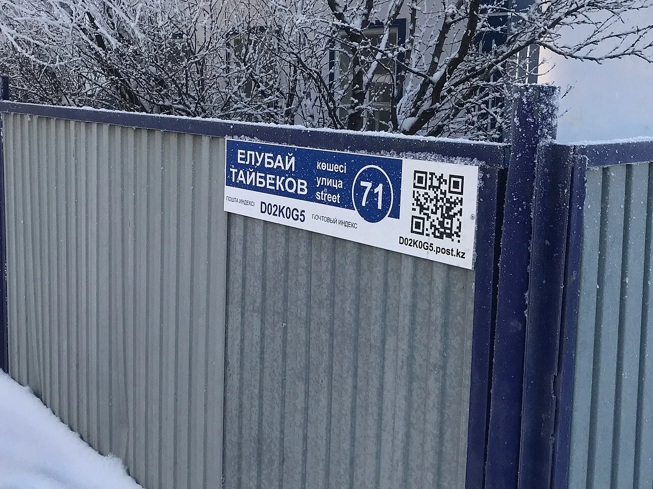 阿克托比：「ЕРҒАЛИ ТАЙБЕКОВ／ЕРГАЛИ ТАЙБЕКОВ」為街名人物，圓框中的71為門號，右側另有QR碼。