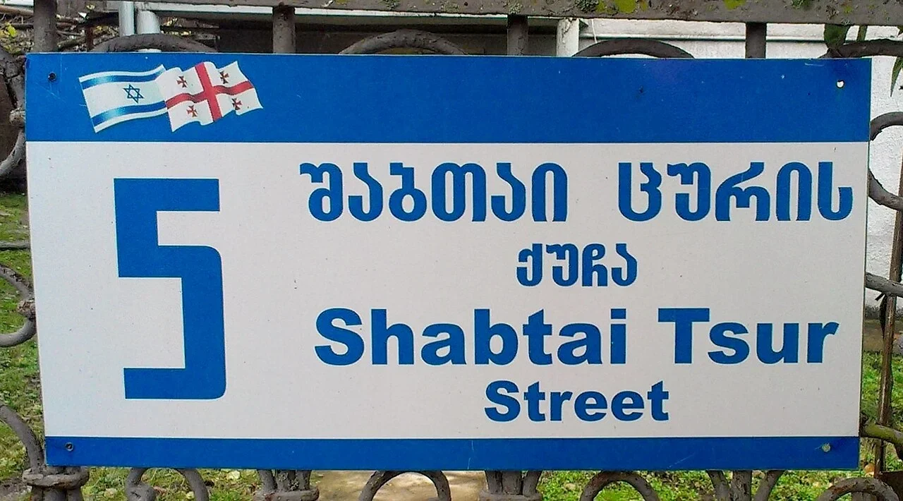 瓦尼：「Shabtai Tsur Street」與喬治亞文是沙卜泰・祖爾街；左側5為地址數字，頂端為兩國旗幟圖樣。