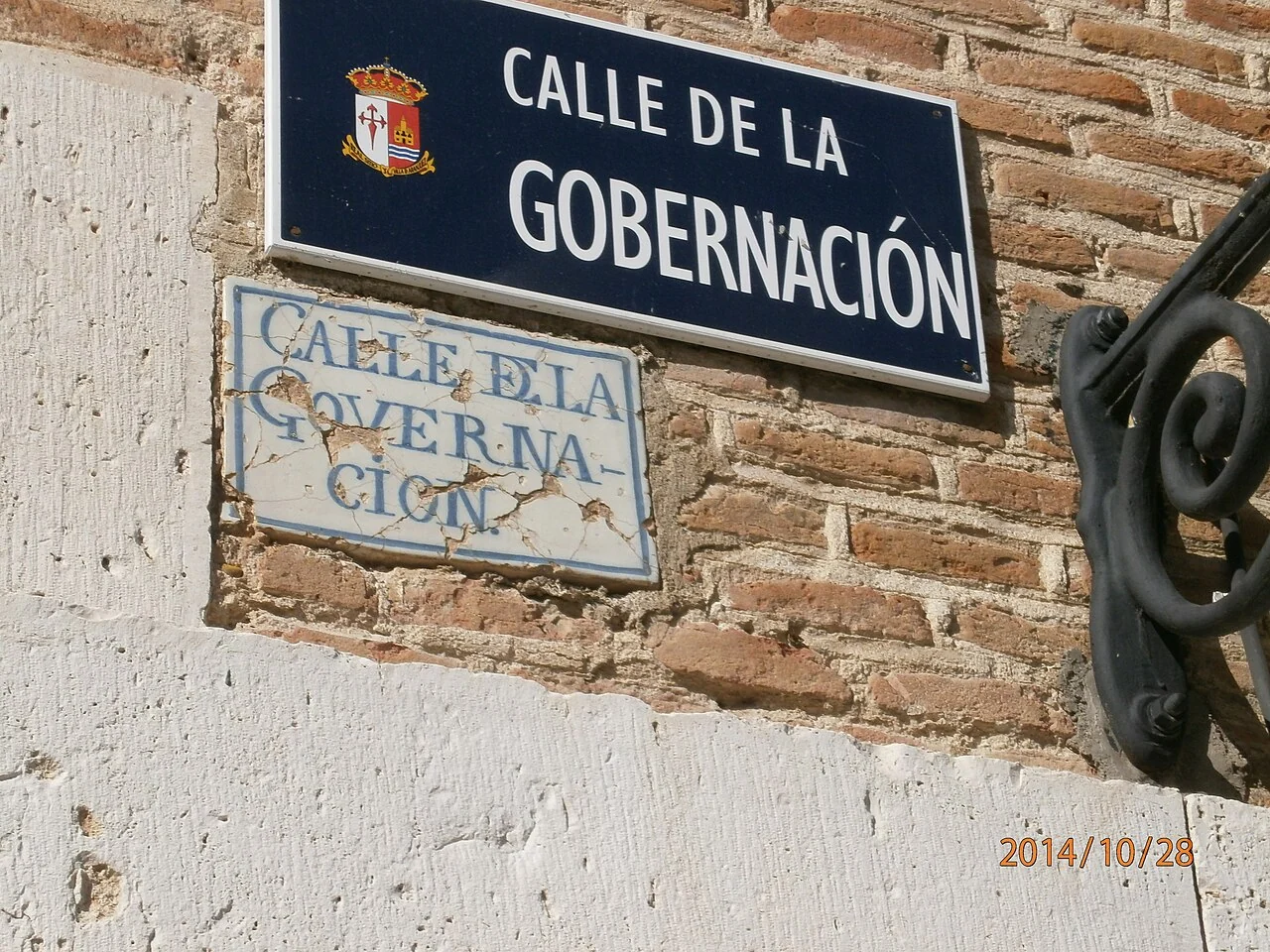 阿蘭胡埃斯的實拍街牌。上方「CALLE DE LA GOBERNACIÓN」與下方分行舊牌對應同一街名;底部日期是照片印記,不是門牌。