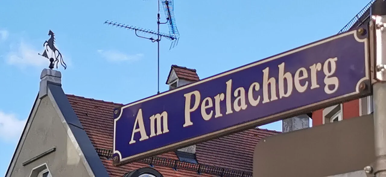 奧格斯堡的實拍街牌。「Am Perlachberg」是街名；牌面未列門牌，右端彎折部分沿著立柱安裝。