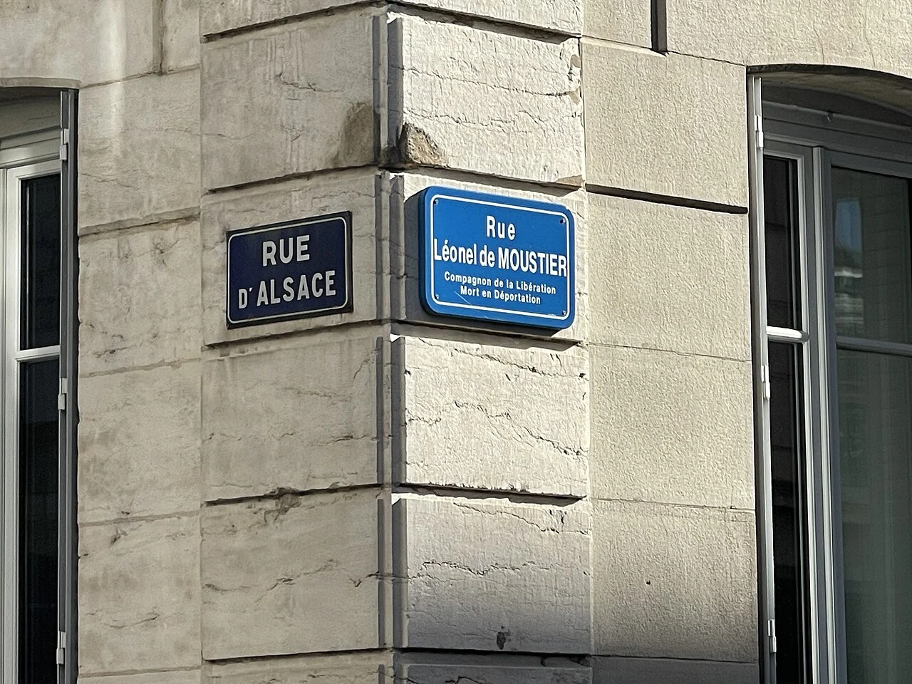 貝桑松的實拍街牌。左牌「RUE D’ALSACE」，右牌「Rue Léonel de MOUSTIER」；兩者是相交道路的名稱。