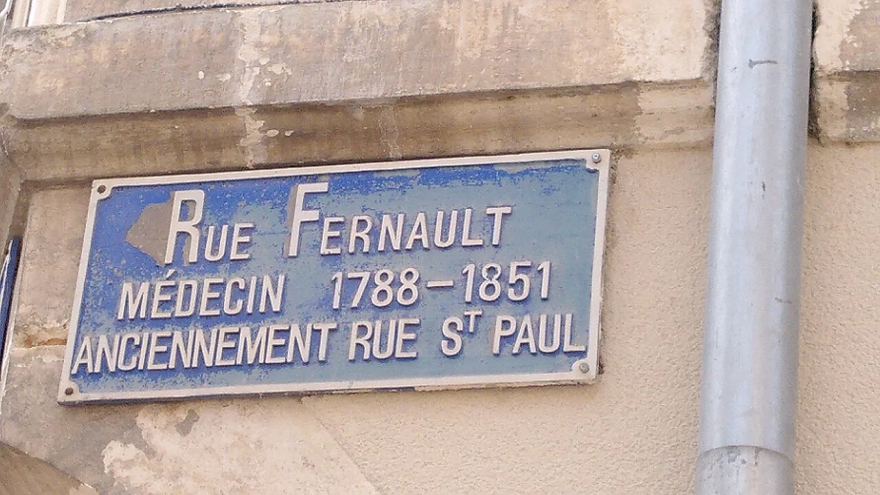 布爾日的實拍街牌。「RUE FERNAULT」為現名;下方「MÉDECIN 1788–1851」是人物資訊,「ANCIENNEMENT RUE St PAUL」列出舊名。