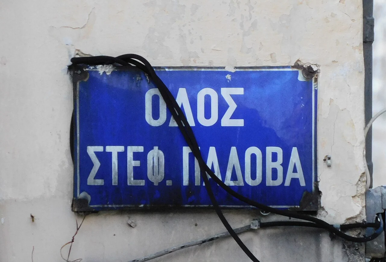 科孚城的實拍街牌。「ΟΔΟΣ ΣΤΕΦ. ΠΑΔΟΒΑ」為街名；ΣΤΕΦ.保留縮寫，ΟΔΟΣ是街道用字，黑色電線遮過部分牌面。