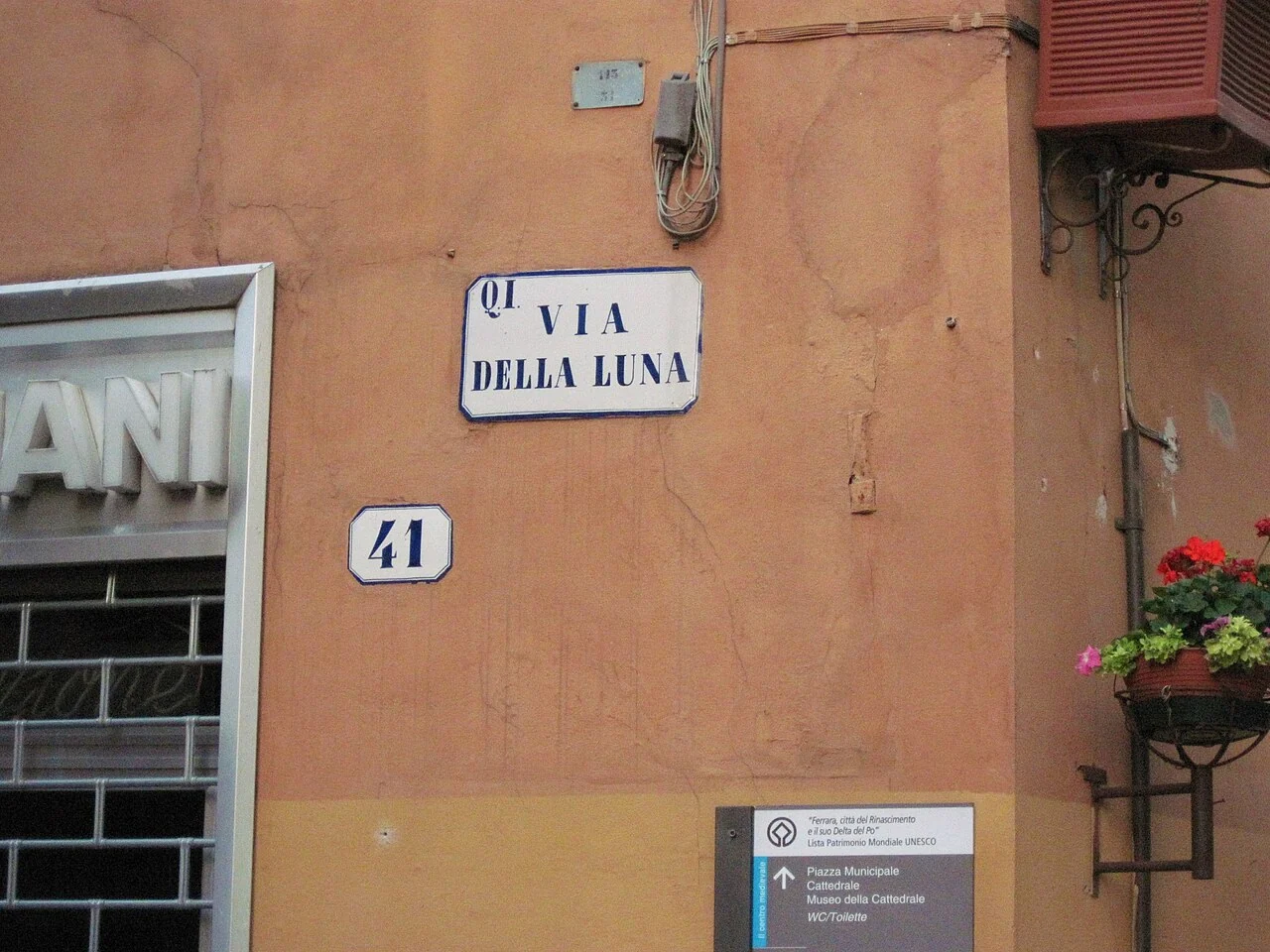 費拉拉的實拍街牌。主牌「VIA DELLA LUNA」是街名，下方獨立小牌「41」為門牌；左上還有小型區域標記。