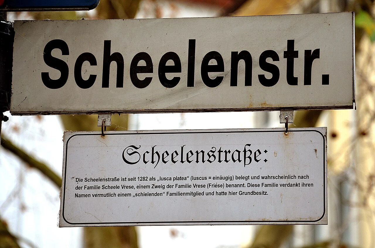 希爾德斯海姆的實拍街牌。上方「Scheelenstr.」為Scheelenstraße的縮寫；下方另一塊牌以完整街名及小字補充解說。