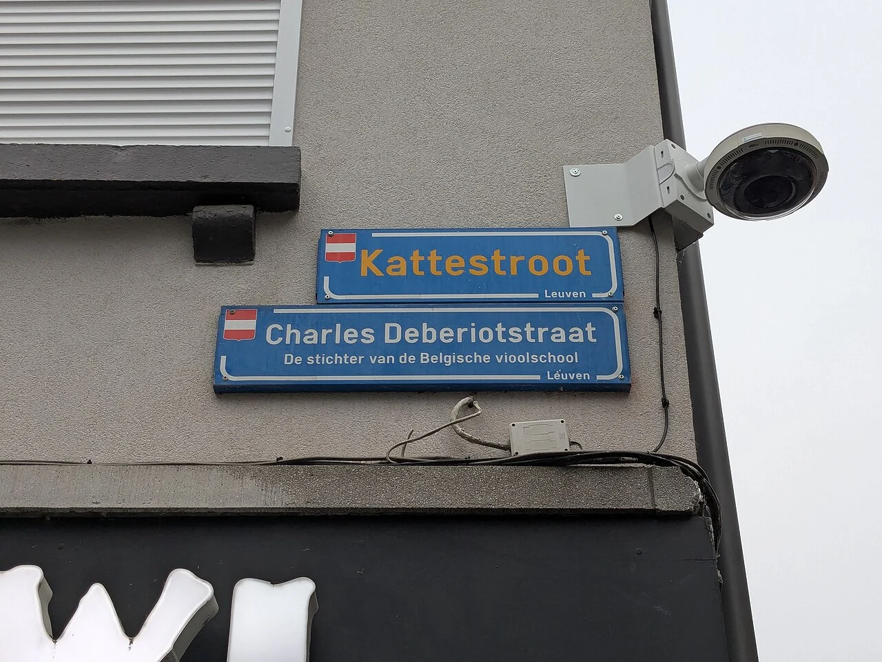 魯汶的實拍街牌。上牌「Kattestroot」與下牌「Charles Deberiotstraat」並列；下牌另有小字人物解說。