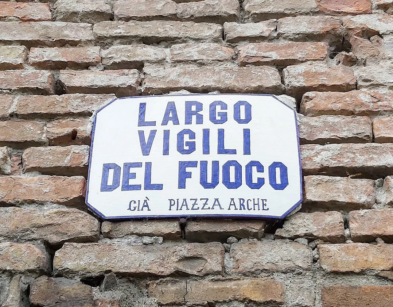 曼托瓦的實拍街牌。「LARGO VIGILI DEL FUOCO」是現名；下方「GIÀ PIAZZA ARCHE」表示曾稱Piazza Arche。