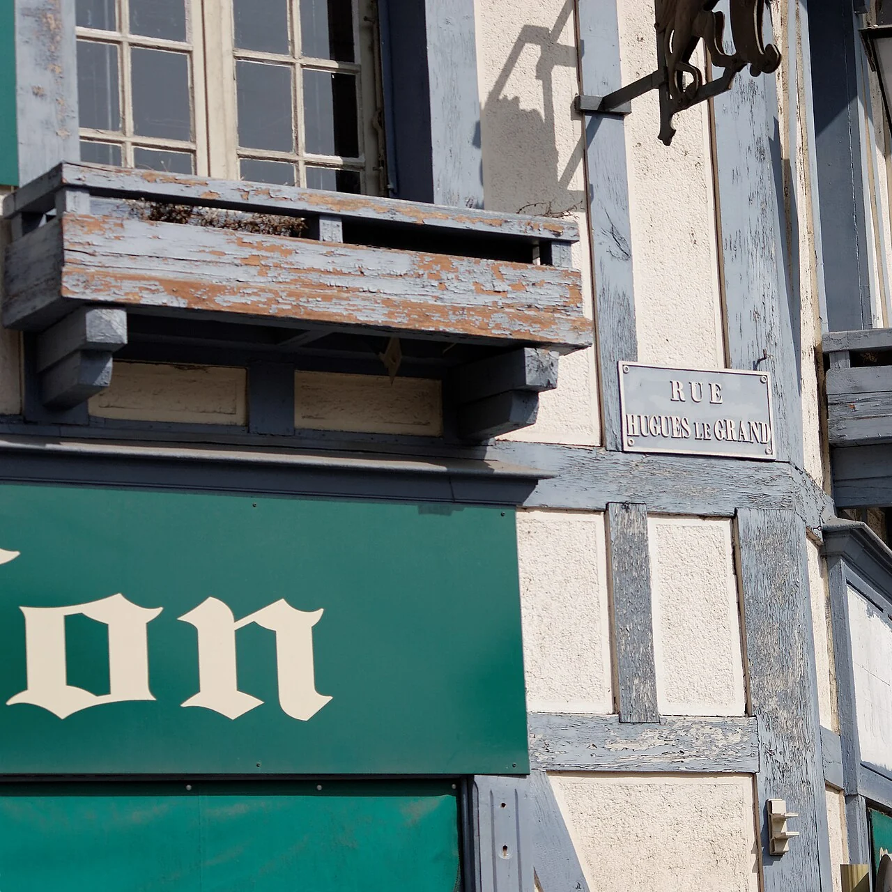 普羅萬的實拍街牌。牆上淡色牌讀「RUE HUGUES LE GRAND」；下方綠色商店招牌不是街名的一部分。