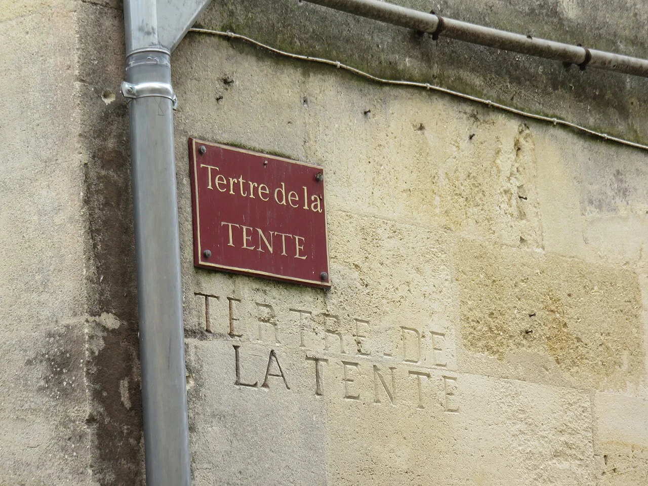 聖埃米利永的實拍街牌。紅牌「Tertre de la TENTE」與牆面刻字「TERTRE DE LA TENTE」相對應，並非兩個地址。