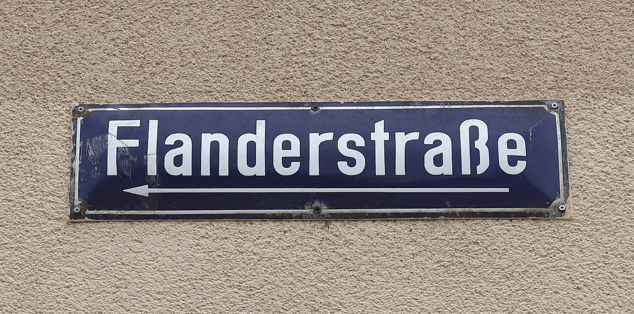 特里爾的實拍街牌。「Flanderstraße」為街名；下方朝左箭頭表示方向，並非文字底線。