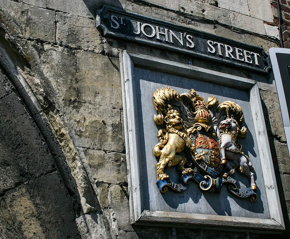 索爾茲伯里的實拍街牌。ST. JOHN'S STREET 為街名；下方紋章是另一個立面元素。