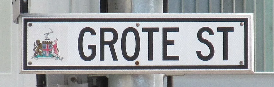 阿得雷德白底黑框GROTE ST街牌特寫，左端有彩色城市紋章，外圍為銀色框。
