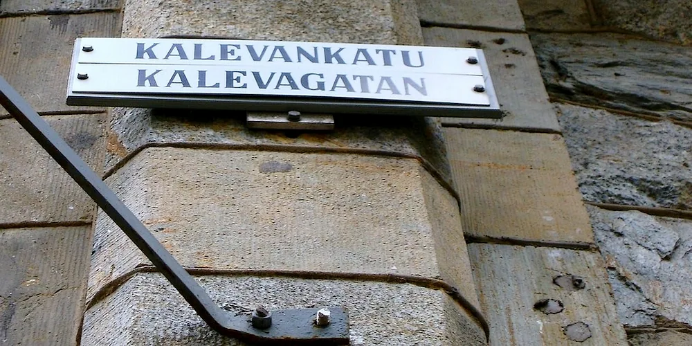 赫爾辛基石牆前的白底雙語路牌，上行KALEVANKATU，下行KALEVAGATAN。
