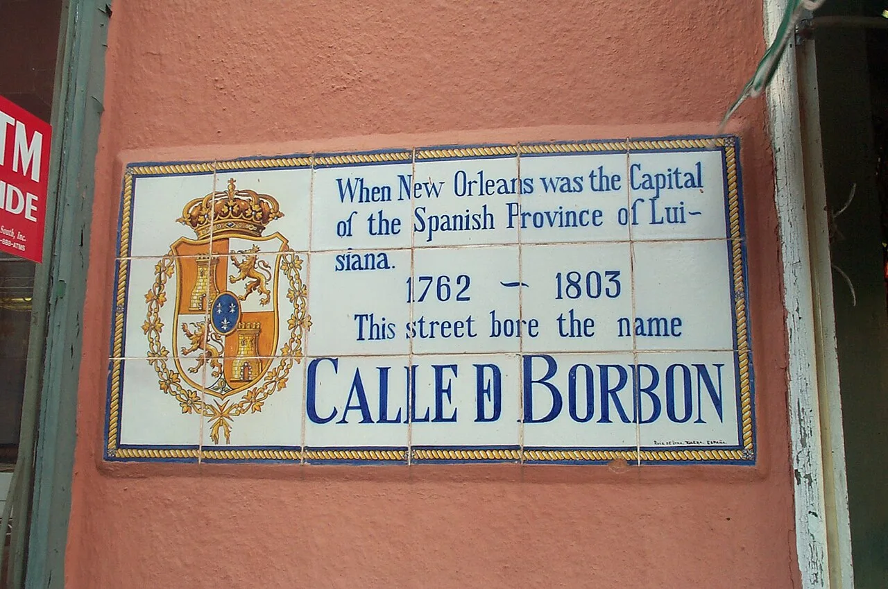 紐奧良赭色牆上拼接陶瓷街名牌,寫CALLE D BORBON及1762–1803,左邊有彩色紋章。