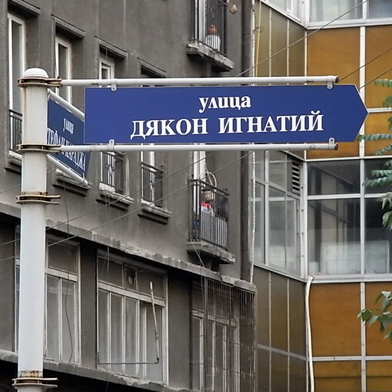 索菲亞藍色箭頭形路牌，上有白色西里爾文улица ДЯКОН ИГНАТИЙ，固定在灰色橫桿上。