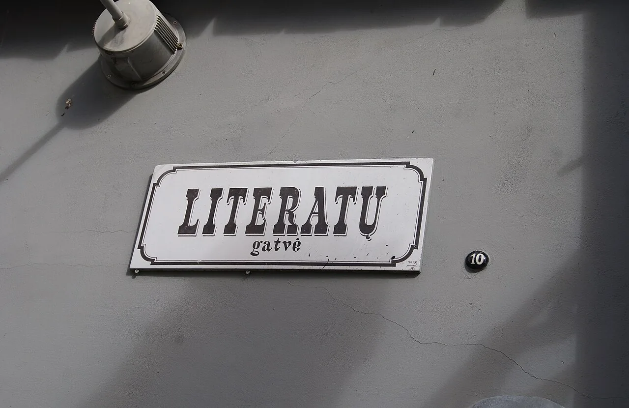 維爾紐斯淺色牆上的LITERATŲ gatvė裝飾街牌，旁邊是黑底白字10號橢圓門牌。
