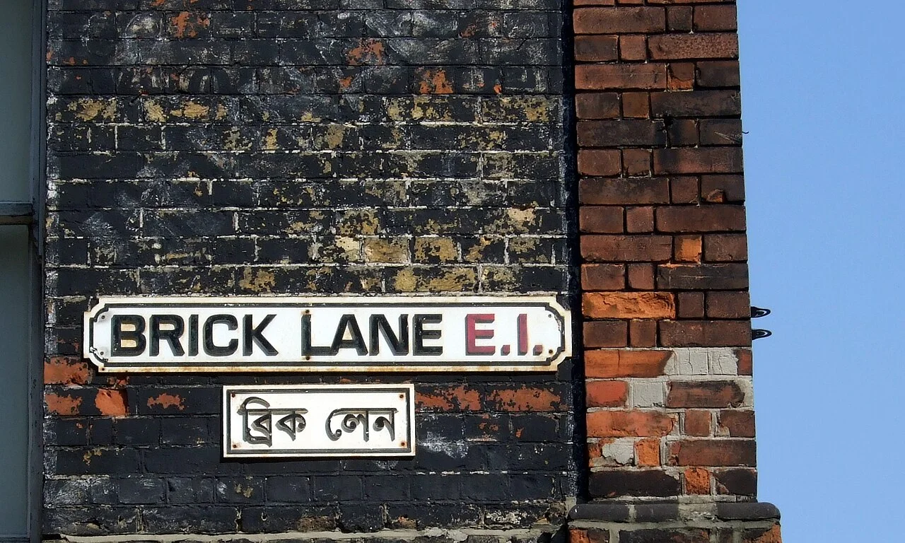 倫敦Brick Lane磚牆上的英文街牌與下方孟加拉文街牌。