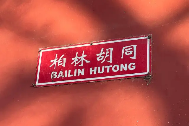 北京牆面上的紅色柏林胡同街牌，白色中文字下方有大寫拼音 BAILIN HUTONG。