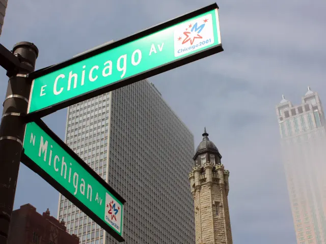 芝加哥路口綠底白字E Chicago Av與N Michigan Av街牌，旁有Chicago 2001小圖樣。