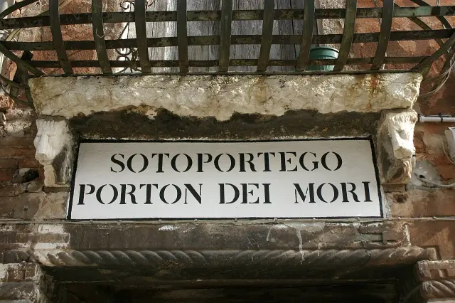 威尼斯磚石門楣上的黑框白底牆面字樣，寫Sotoportego Porton dei Mori。