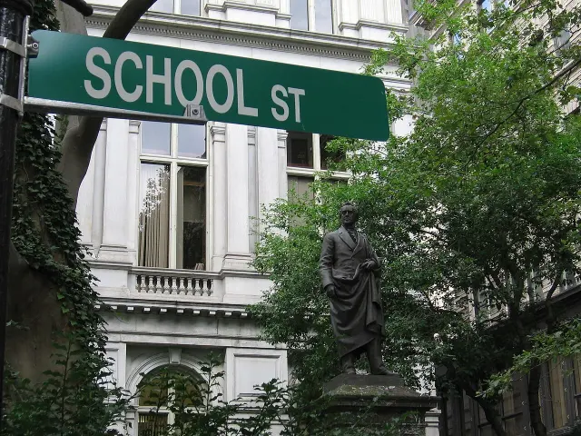 波士頓綠底白字SCHOOL ST街牌，後方可見舊市政廳立面、樹木及人物雕像。