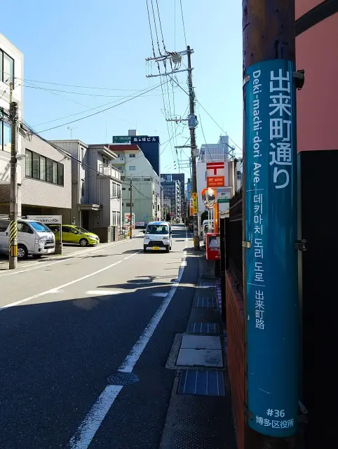 福岡博多出来町通り的藍綠色多語街名標柱，位於街道右側。