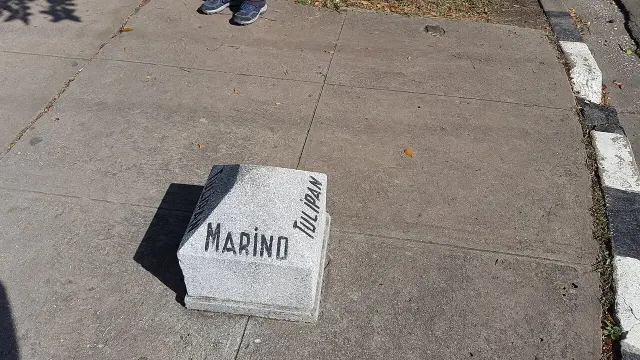 哈瓦那人行道上的淺灰色低矮路標，中央寫MARINO，右側斜向排列TULIPÁN，旁邊是路緣。
