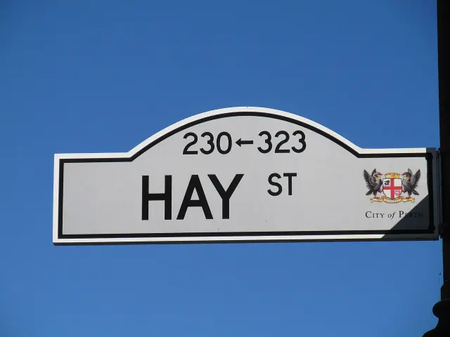伯斯白底黑框拱頂Hay St街牌，上方為230左箭頭323，右側有City of Perth紋章，背後是藍天。