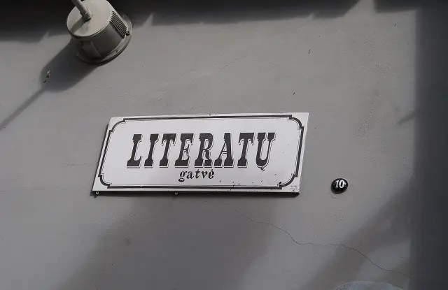 維爾紐斯淺色牆上的LITERATŲ gatvė裝飾街牌，旁邊是黑底白字10號橢圓門牌。