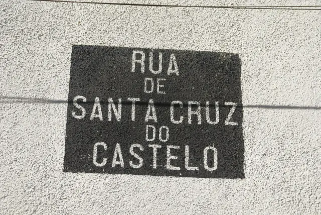 里斯本Castelo街區的牆面，黑底白字寫著Rua de Santa Cruz do Castelo。